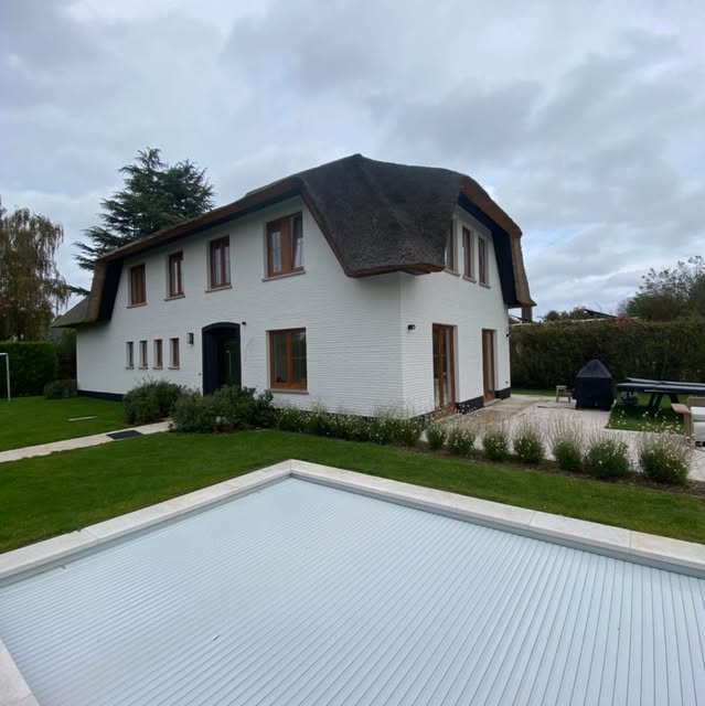 Wit geschilderde villa met rieten dak en zwembad