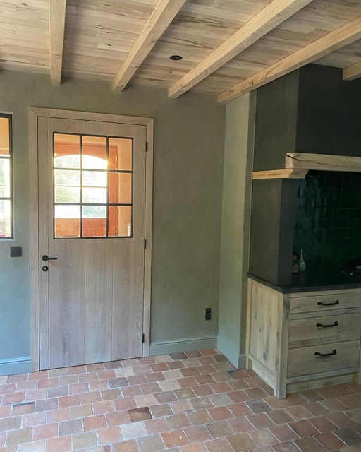 Landelijke leefkeuken met wanden in kalkverf, eiken balken en terracotta vloer